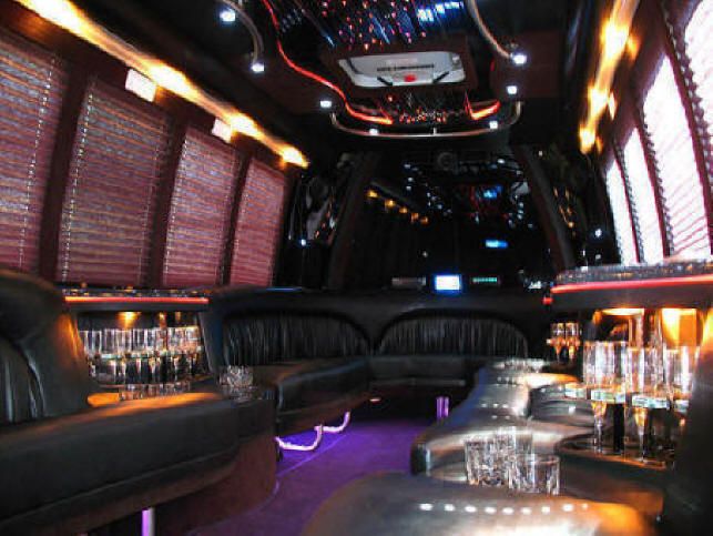 image is showing a party bus interior - black seats and wine glasses