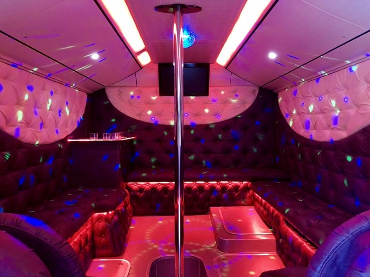 pink and purple party bus interior with a pole
