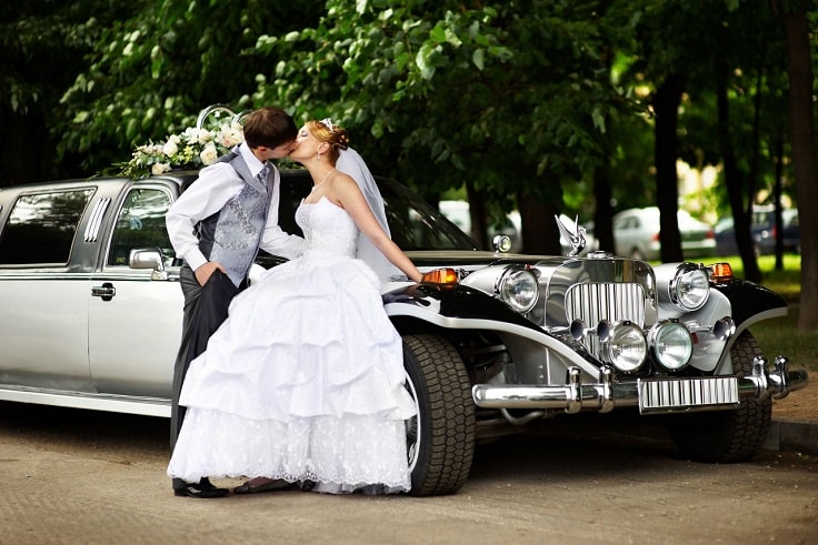 image is showing kissing newlyweds and old fashion limo